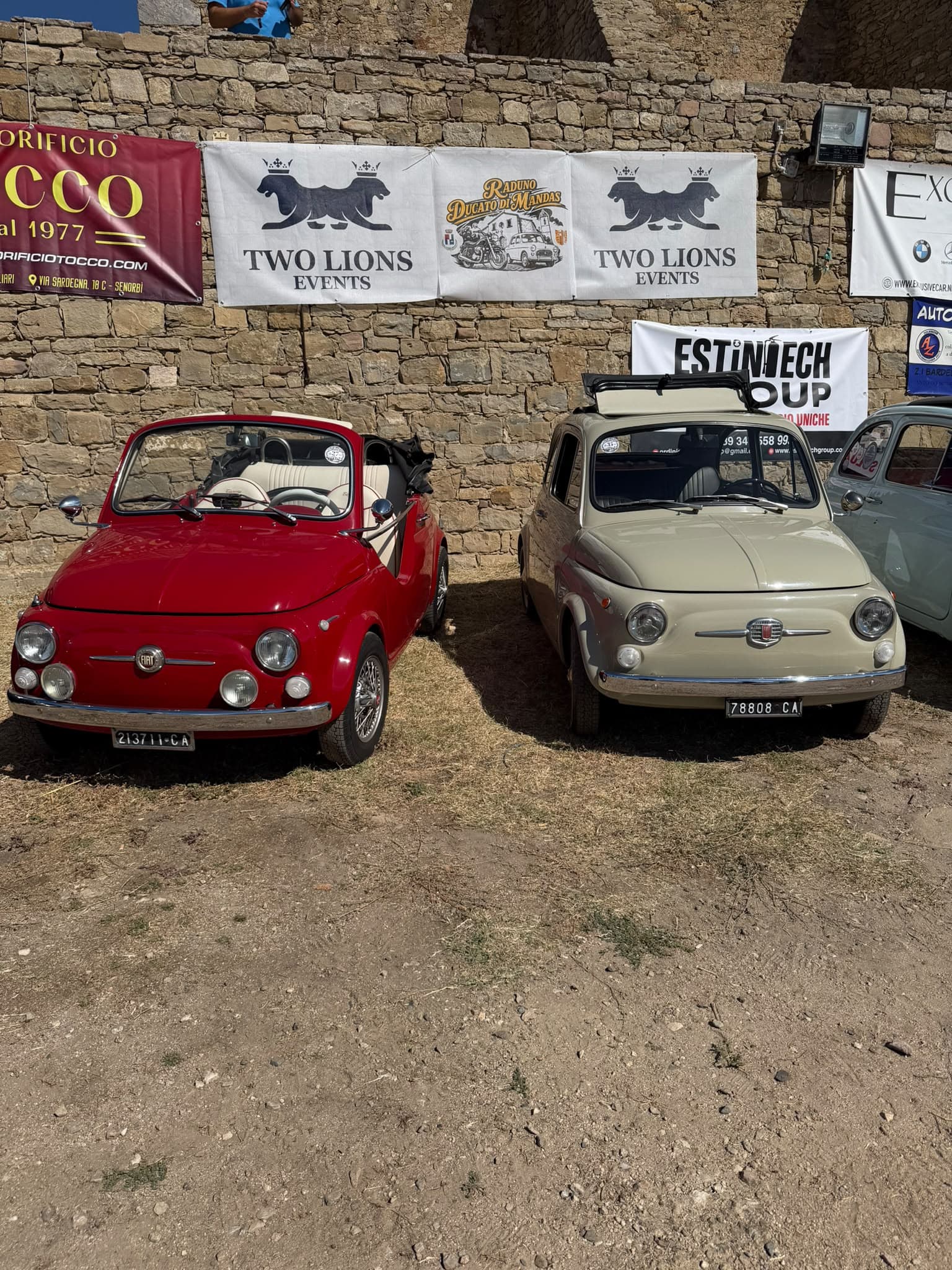 Official Two Lions Events and Ducato di Mandas Rally banners above classic Fiat 500s