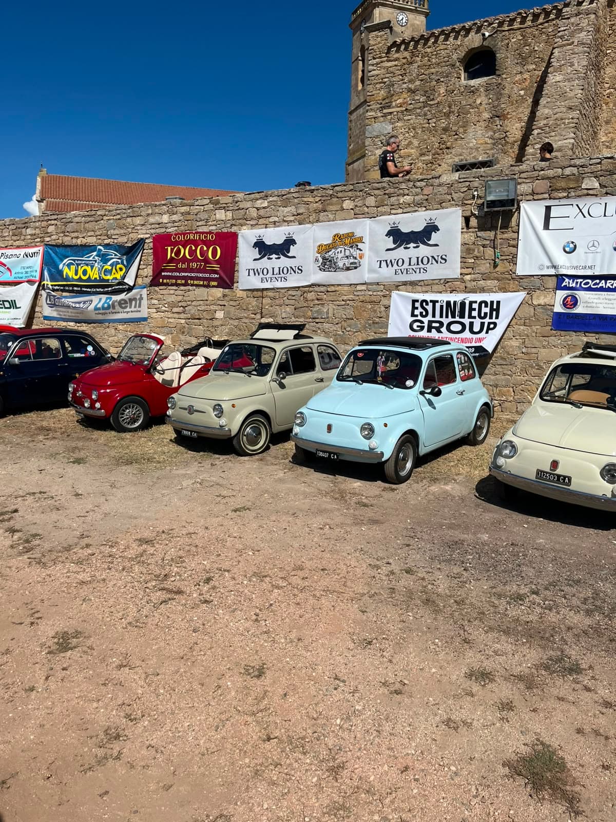 Historic stone architecture of Mandas with classic cars and Two Lions Events banners